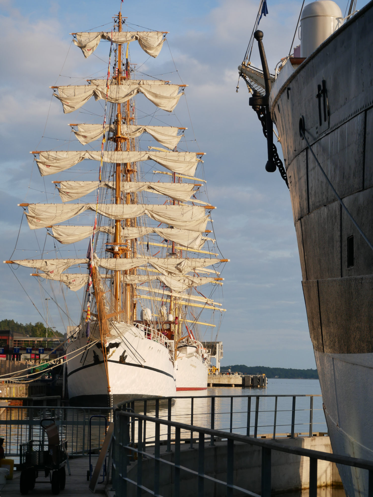 Två skepp syns på rad, förtöjda i hamn. I förgrunden syns fören av Pommern i dess docka.