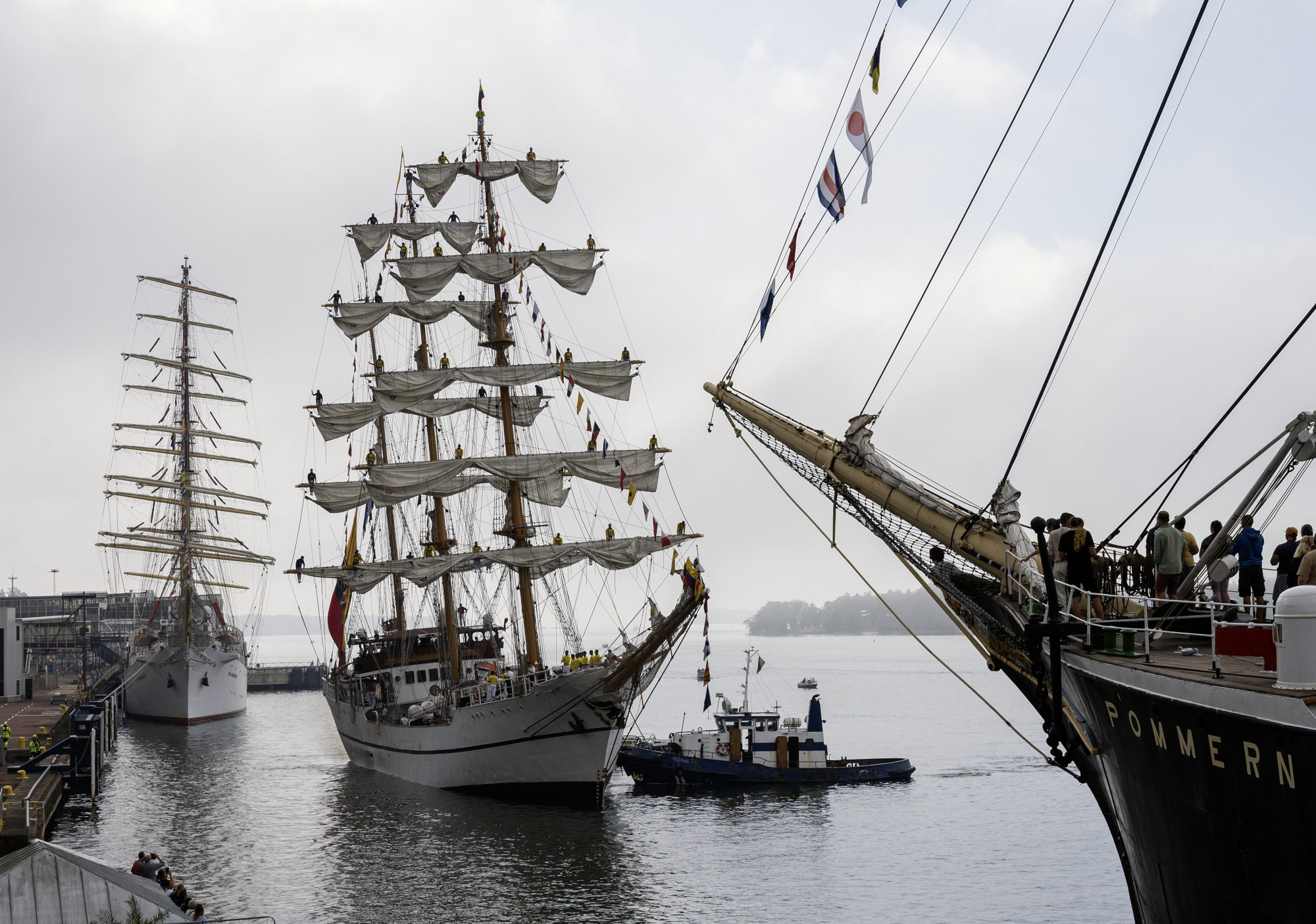 Bugue Escuelas Guayas med lotsbåt tar i hamn i Mariehamn. I bakgrunden skymtas ett annat skepp och i förgrunden ses Pommerns för.